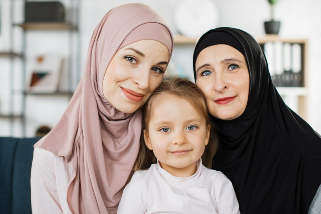 Portrait of happy three generations of muslim women hug and cuddle posing at home