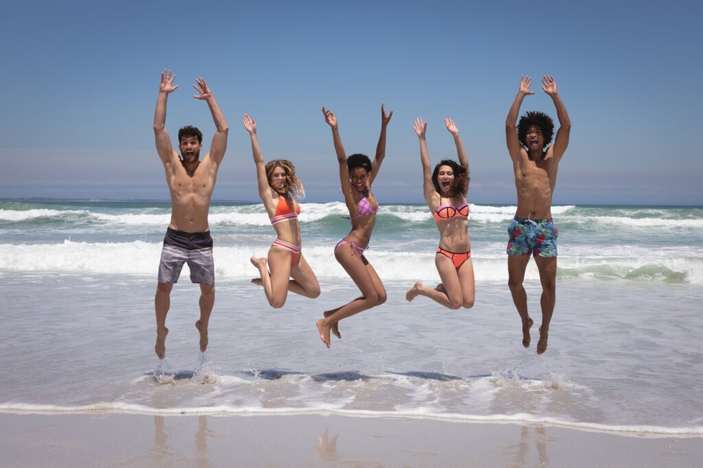 Friends jumping together on beach